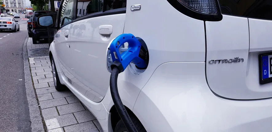 Electric vehicle at a charging station, illustrating Cambridge research into extending EV battery lifespan