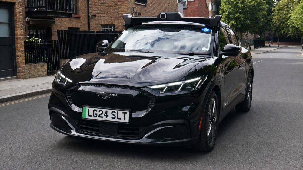 One of Wayve's autonomous vehicles, a black Ford Mustang Mach-E with a roof-mounted sensor pod, parked on a London street