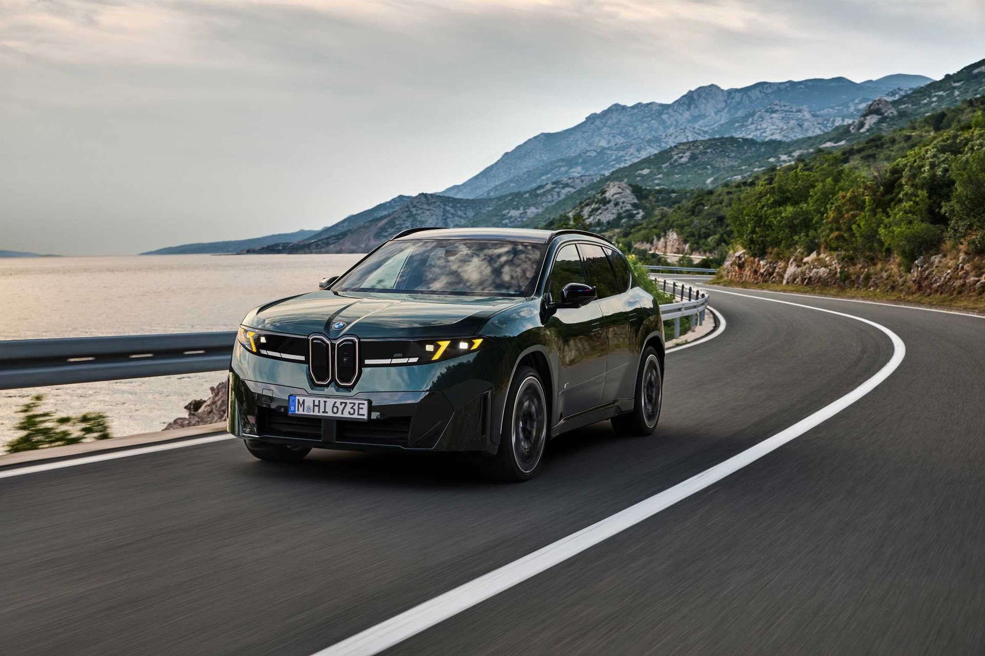 BMW iX3 M60 xDrive in dark green cornering on a coastal road