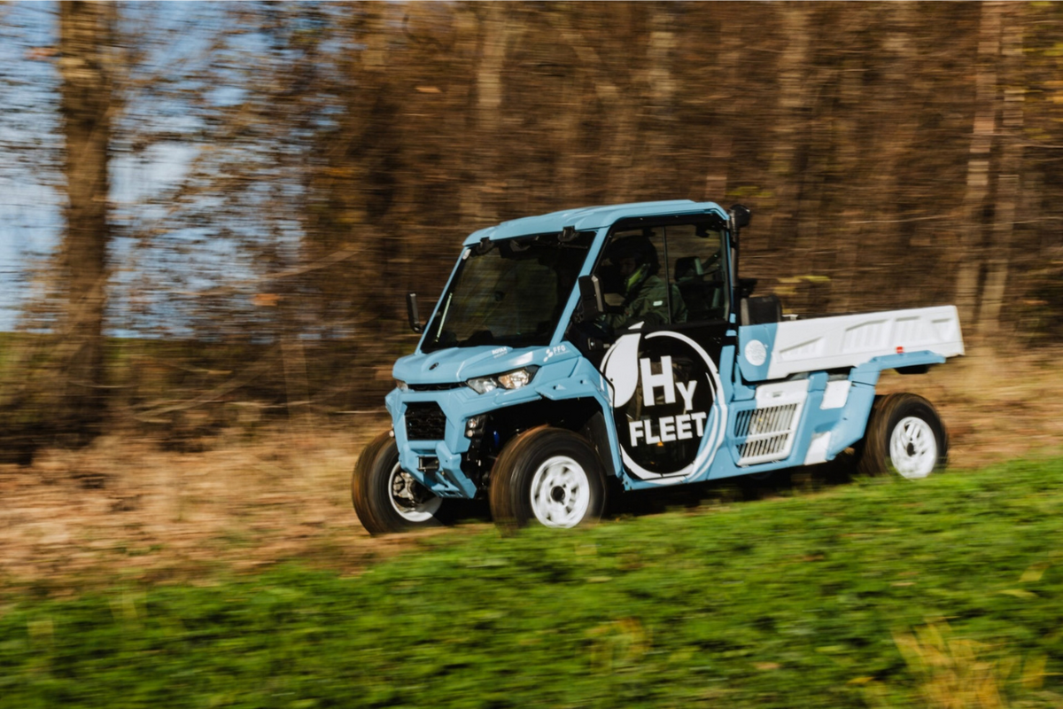 BRP-Rotax HyFleet hydrogen side-by-side vehicle, powered by the EKPO NM12 fuel cell stack, driving across a grass slope beside woodland